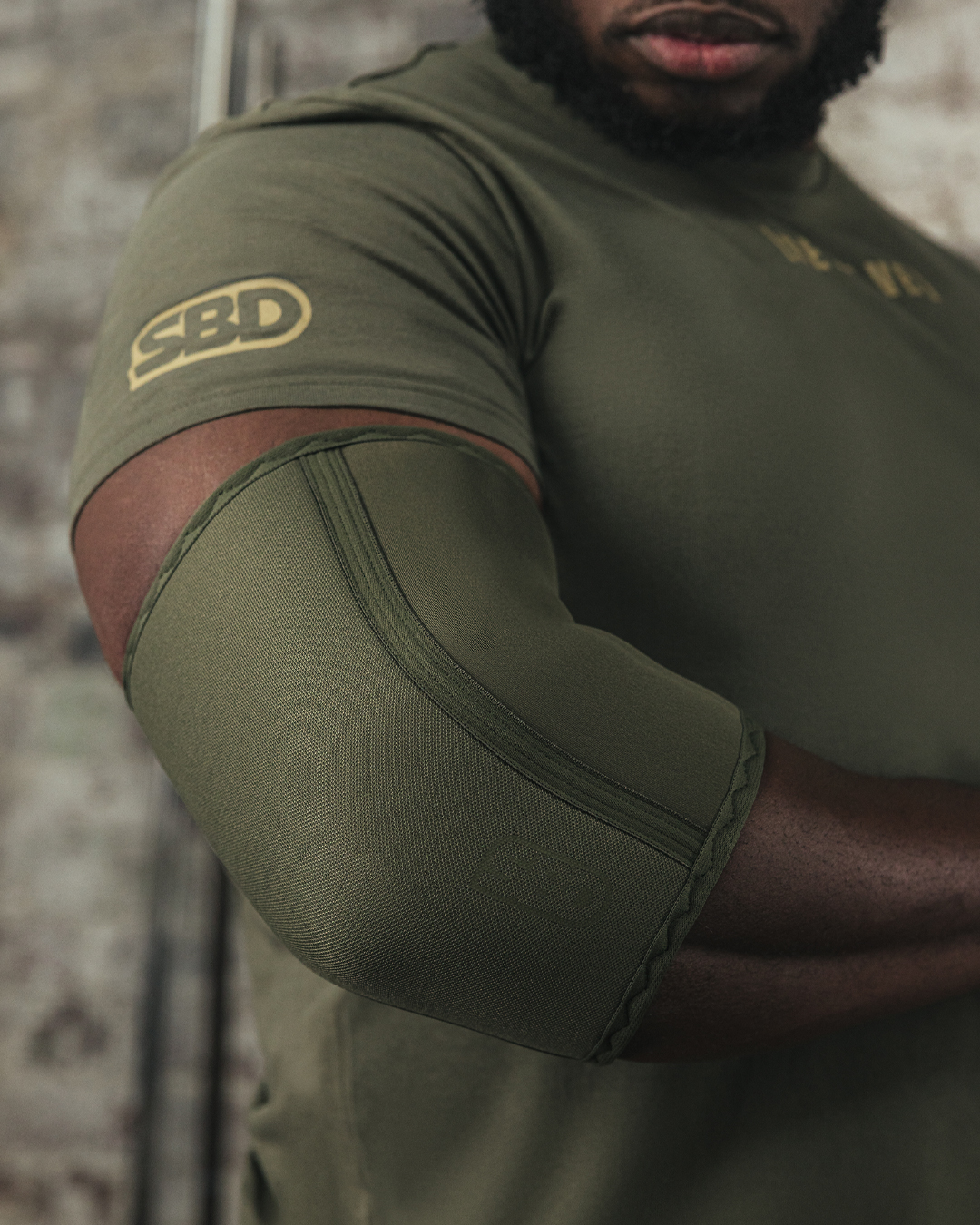 Coudières SBD de couleur kaki en néoprène de 7 mm offrant maintien, compression et confort pour la musculation, le strongman et le streetlifting.